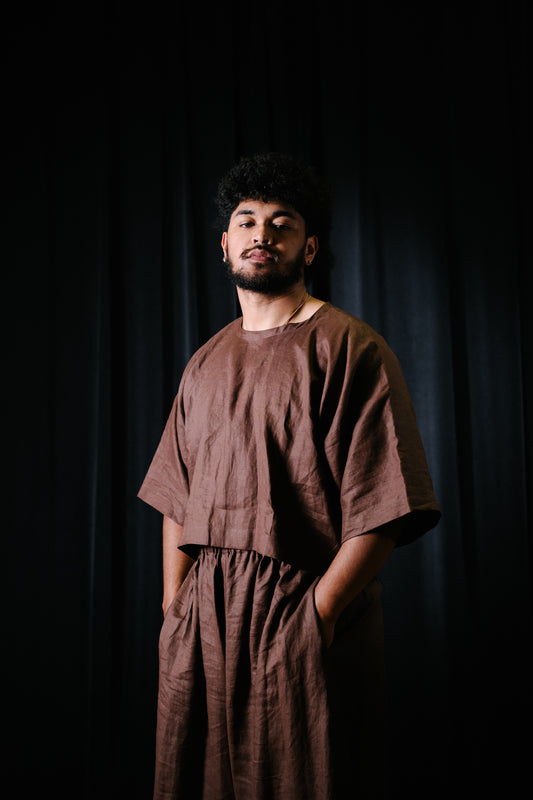 Pacific artist, Keciano wearing a brown linen crop top with matching wide leg pants in a theatre