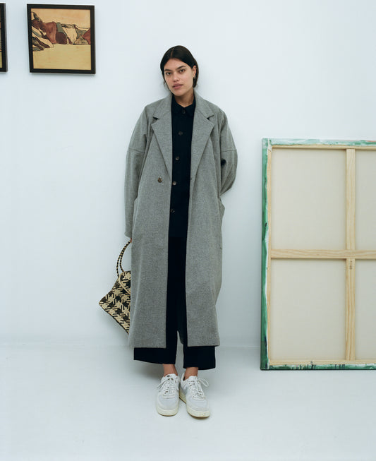 Karen Valerie wearing a long grey wool coat in a gallery
