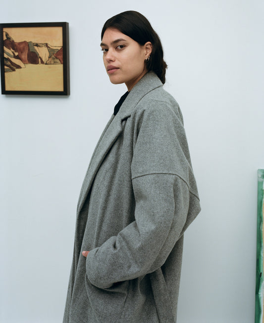 Karen Valerie wearing a long grey wool coat in a gallery