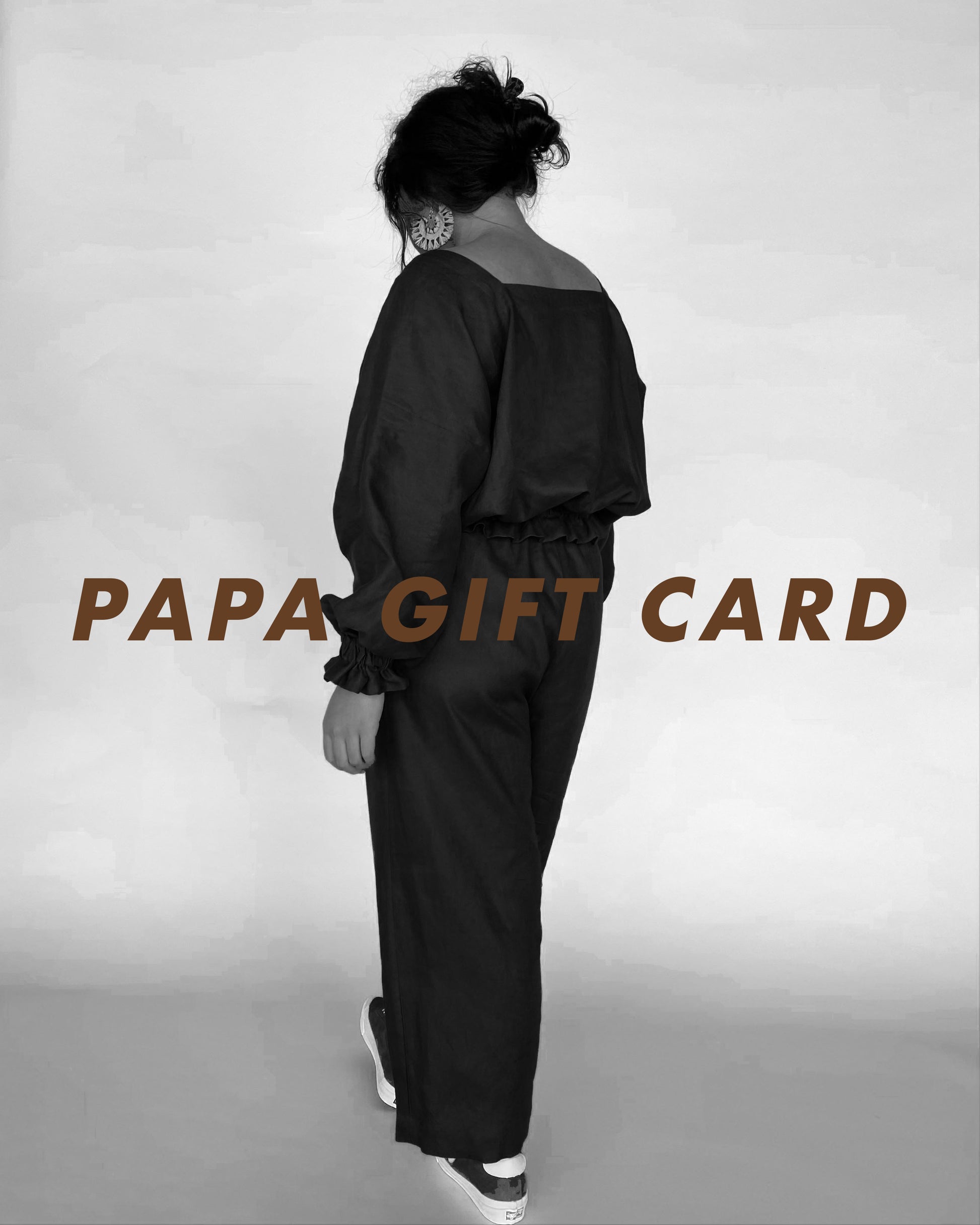 Jalaina wearing a papa clothing linen outfit with her back to the viewer. Text reading PAPA GIFT CARD written over image in brown text