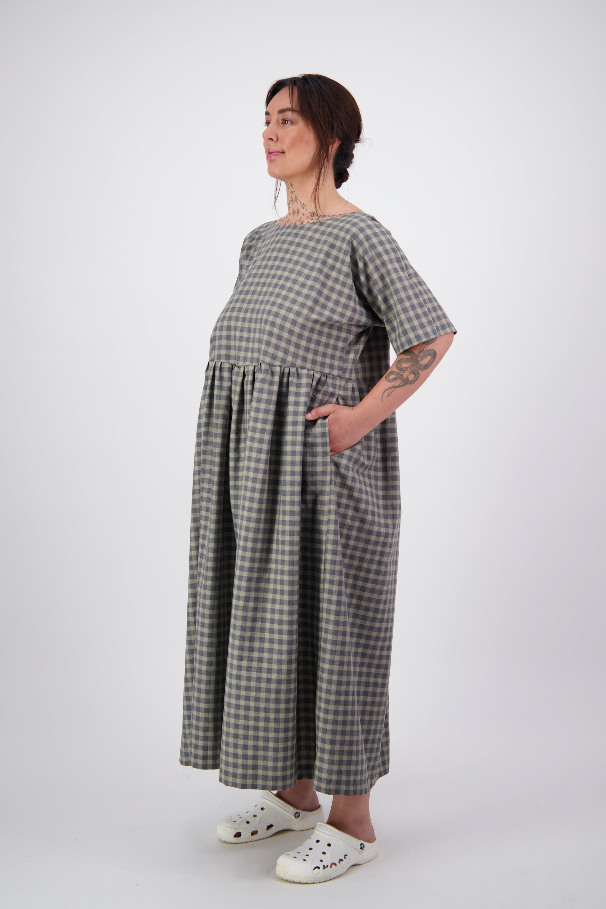 Arlena wearing grey tone check reversible dress with short sleeves and gathered waist showing pockets