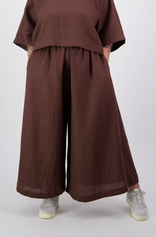 Woman wearing brown linen wide leg flared pants with pockets