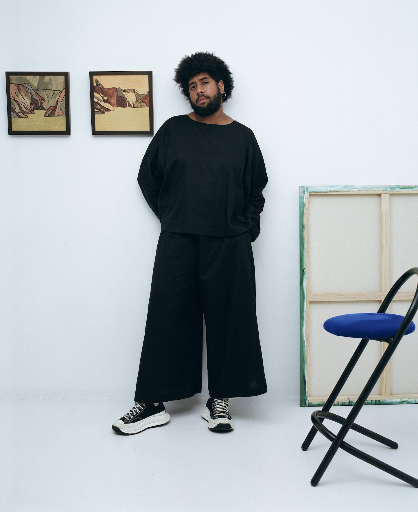 Peter Wing wearing a black long sleeve linen cotton top with matching black linen cotton wide leg pants in an art gallery 