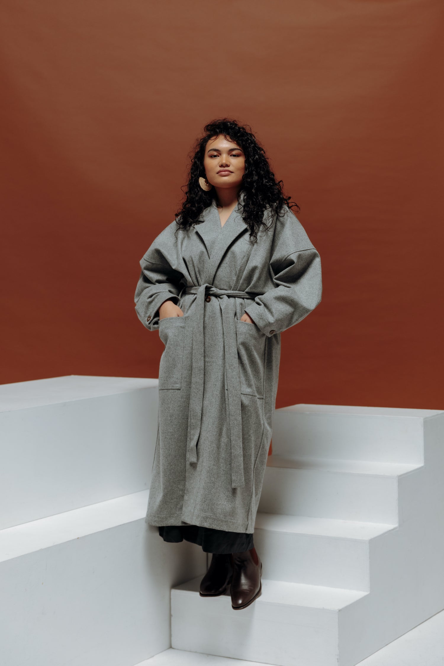Jalaina wearing a long grey wool coat with hands in pockets